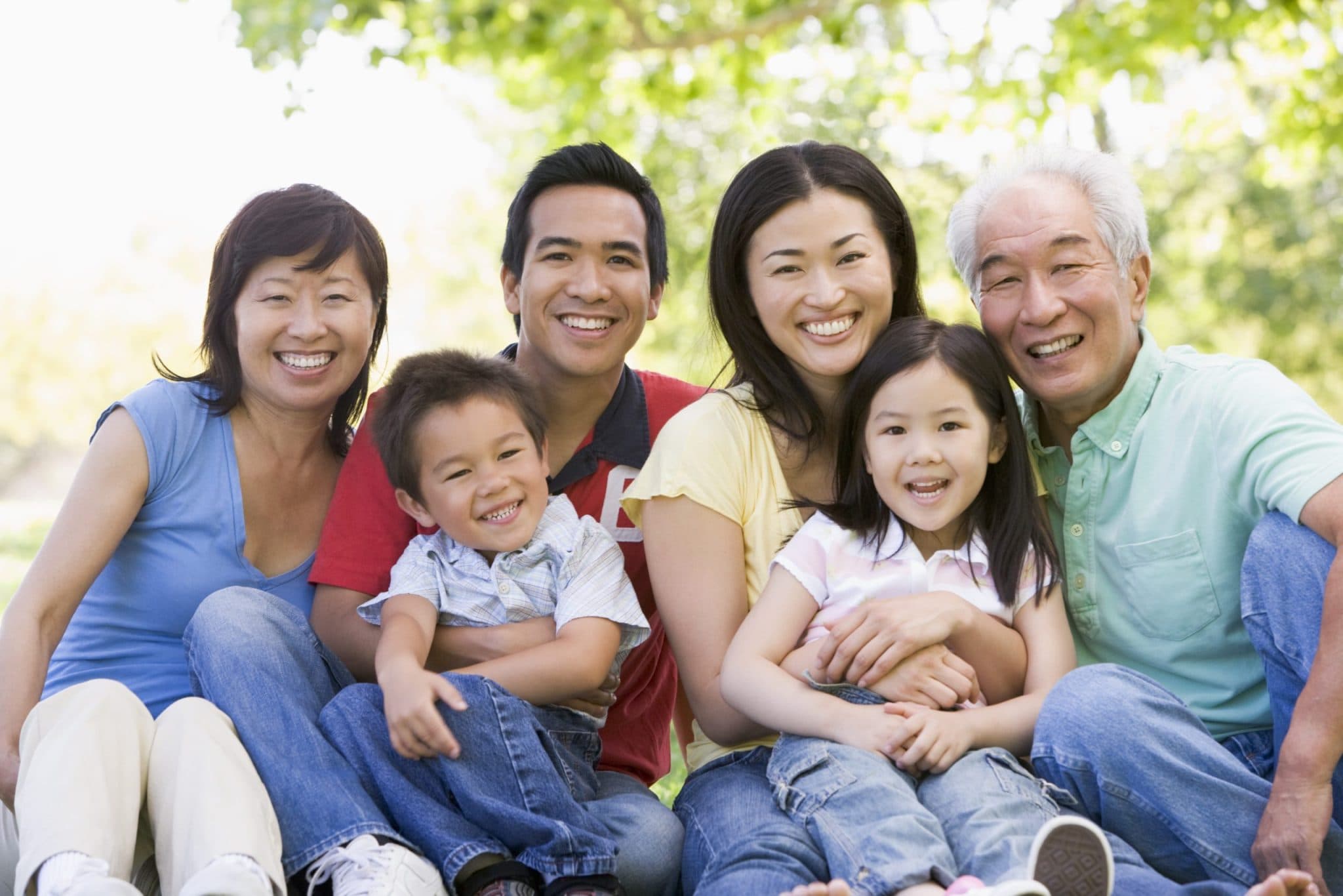 a family sitting together on a couch, smiling with a plant in the background